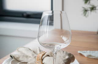 Et Odyssé glass fra Hadeland Glassverk står på et dekket bord.