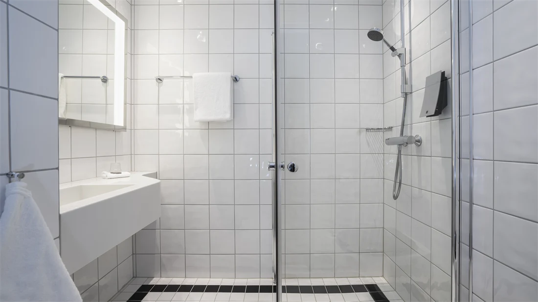 Vask, stort speil med innebygget lys og dusj på bad i enkeltrom på Thon Hotel Opera i Oslo