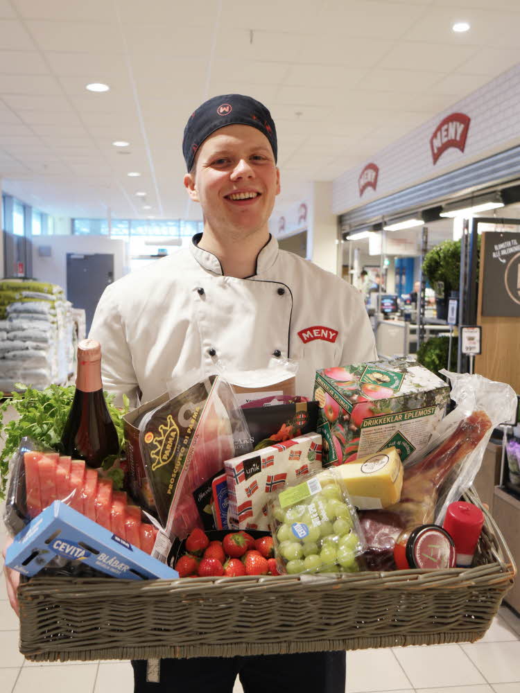 Mann holder korg med 17. mai varer frå MENY