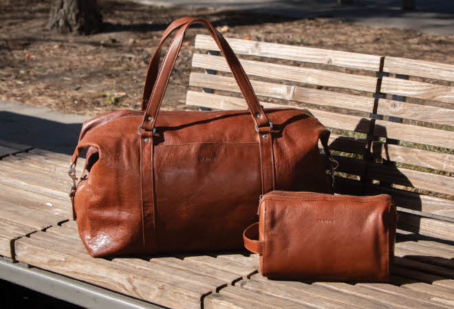 Brun skinnbag og mindre skinnveske på en trebenk utendørs.