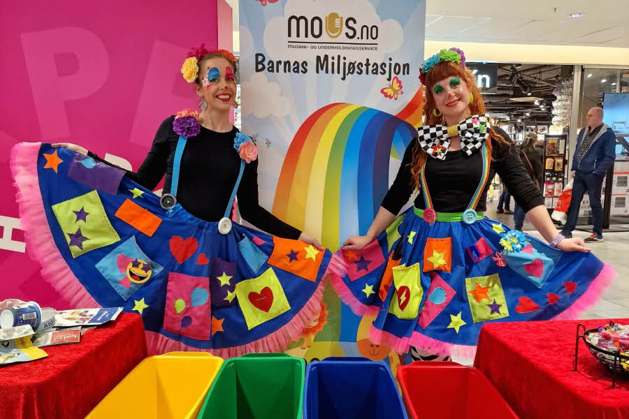 Klovner som smiler til kamera med plakat i bakgrunn med teksten "Barnas Miljøstasjon"