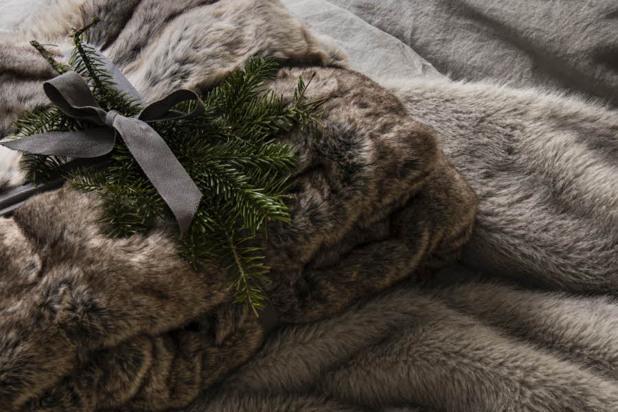 brun pelspledd pakket inn med sløyfe, pyntet med gran eller furu
