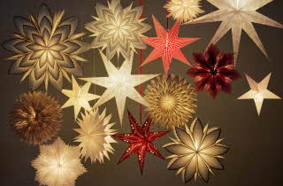 Flere hengende adventsstjerner i ulike størrelser og farger.