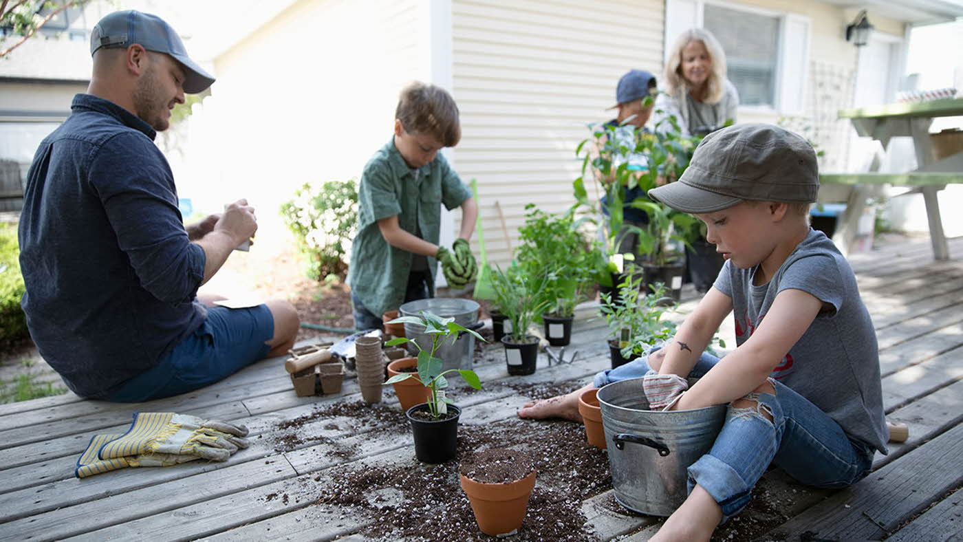 Familie på fem omplanter potter i hagen