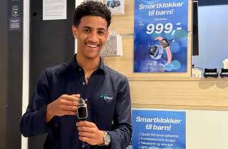 Mann fra Telenorbutikken holder smartklokke til barn