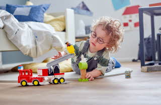 Et barn som ligger på gulvet på rommet sitt og leker med LEGO Duplo