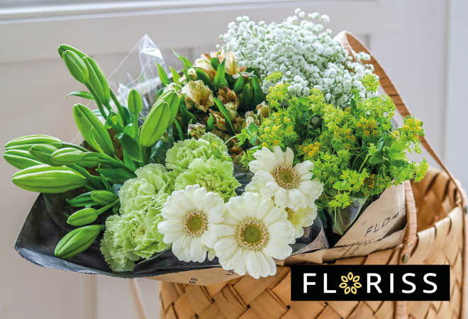 Bukett med blomster i en kurv, inkludert hvite gerberaer og grønne nelliker.