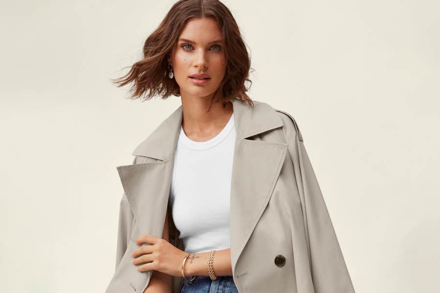 dame som poserer med grå frakk, hvit topp og blå jeans