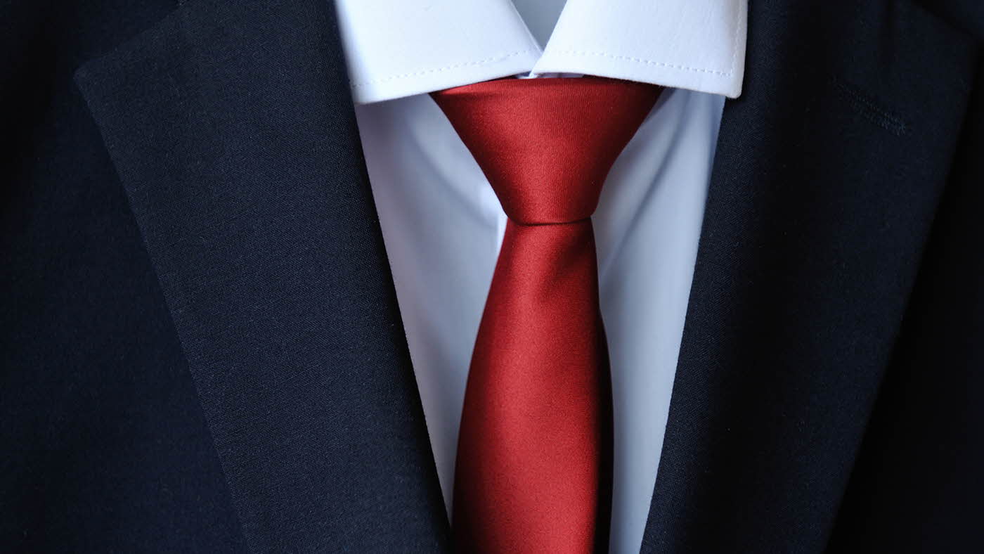 Sløyfe henger fra en dressjakke Utsnitt av brystlommetørkle  Utsnitt av slips på dress