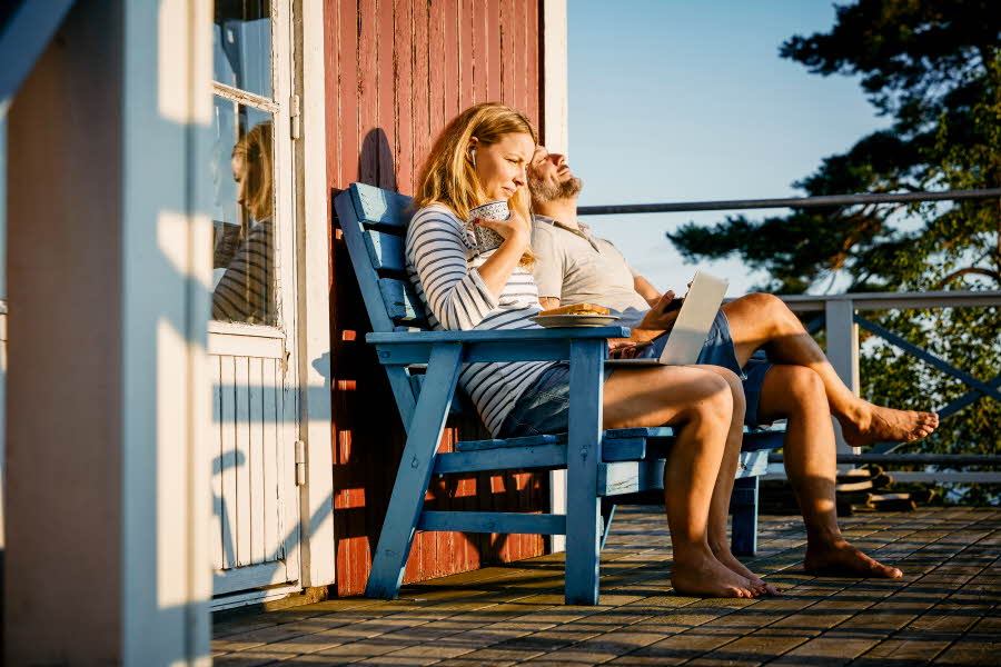 to personer sitter på en blå krakk utenfor hytteveggen