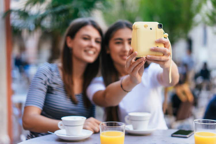 To jenter tar selfie med polaroidkamera