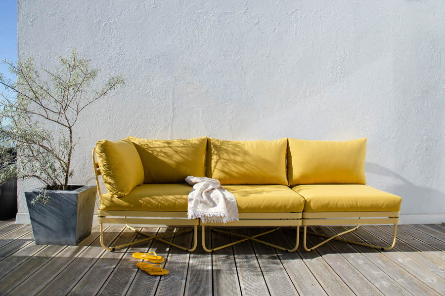 Gull sofa på platt med en grønn plante ved siden av