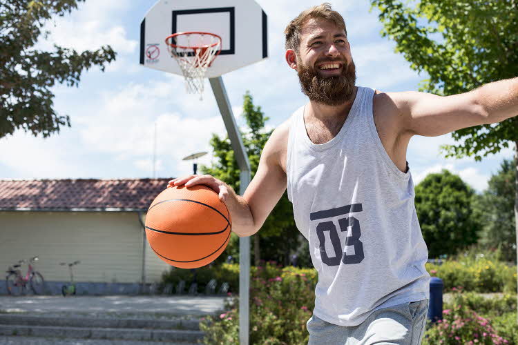 Mann med lys grå singlet med tallet 3 på spiller basket
