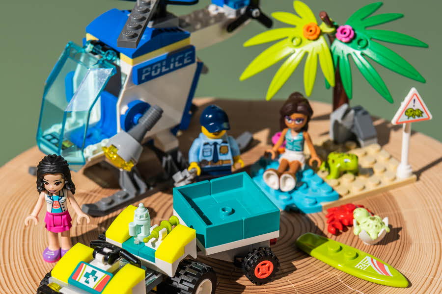 Et lego politi helikopter, et lego palmetre, tre lego figurer og et lego kjøretøy med tilhenger.