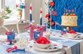 Festlig borddekking med norske flagg og kake.