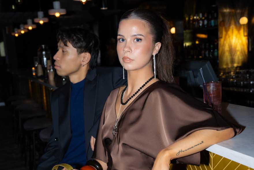 Dame som lener seg på en bar og ser rett i kamera