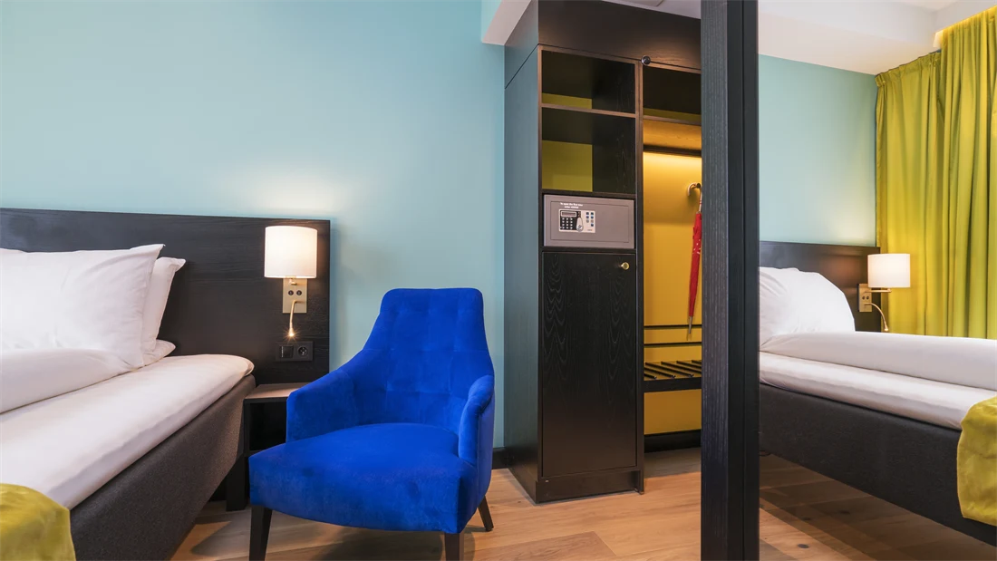 Speil garderobeskap og seng med lenestol ved siden av i dobbeltrom på Thon Hotel Europa i Oslo sentrum rett ved Slottsparken