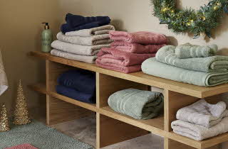 En lav hylle med håndklær og badematter