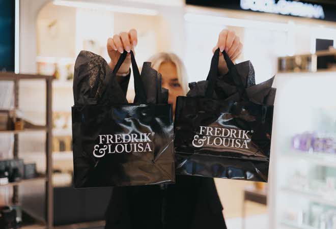 En kvinne viser frem to poser fra Fredrik & Louisa