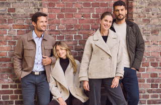 Personer i høstantrekk og lener seg på en murvegg