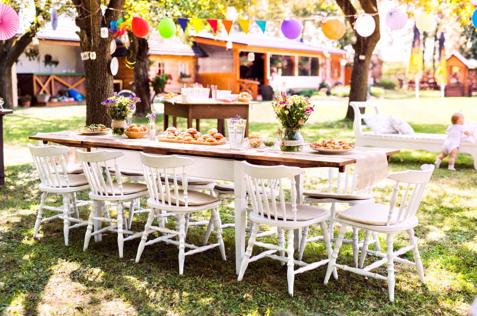 Bord dekket til fest i hagen med ballonger og vimpler
