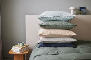 En seng med en stabel med puter i forskjellige farger.