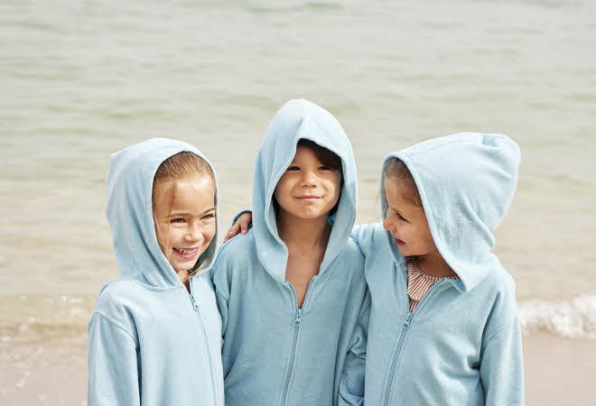 Tre barn som står på en strand