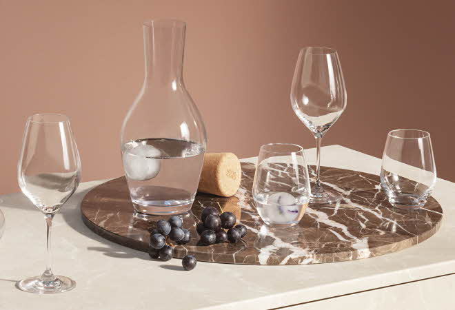 Forskjellige glass og en karaffel fra Holmegaard som står på en plate.