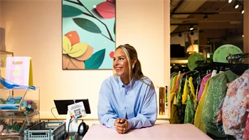 Kaja Sæther, eier av Qomo, står og lener seg på disken til en av butikkene hennes.