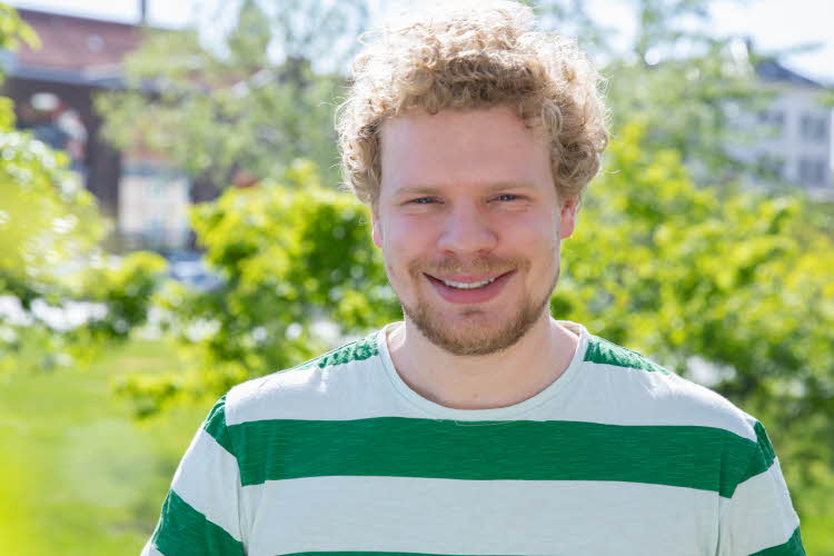 En smilende mann i hvit og grønn-stripede t-skjporte. Simen Faaberg