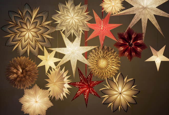 Flere hengende adventsstjerner i ulike størrelser og farger.