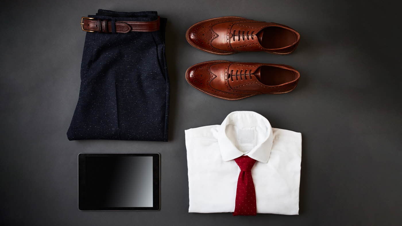Flat lay av antrekk til herre, brettede bukser skjorte og sko