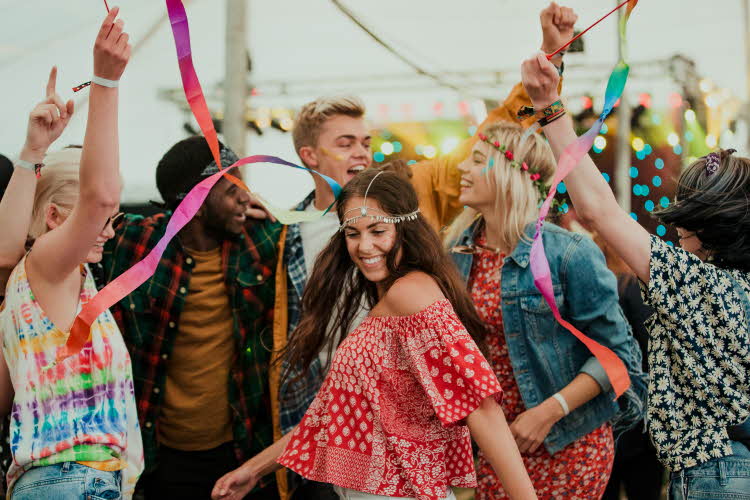 En gjeng som danser på festival i fargerike klær