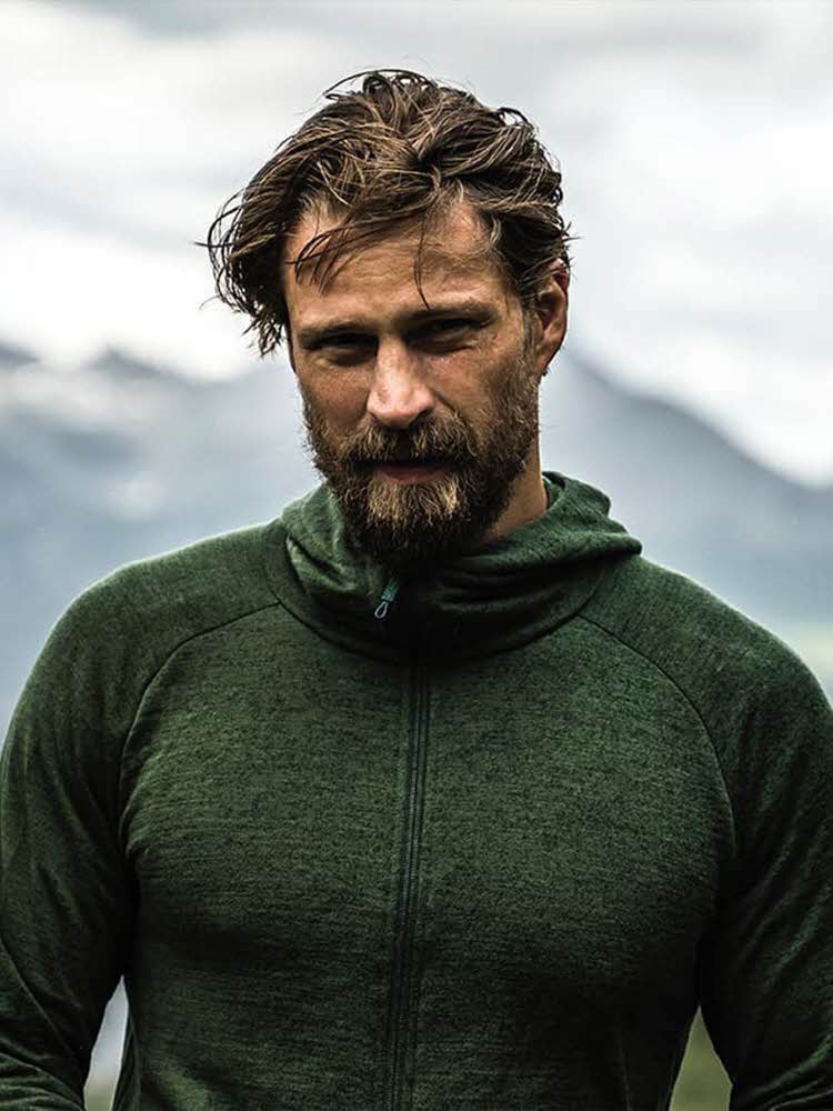 Mann med grønn ulltrøye med fjell i bakgrunn