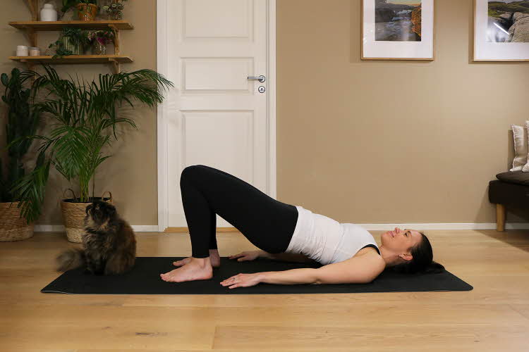 Anna viser Pilates-øvelser på treningsmatte på gulvet