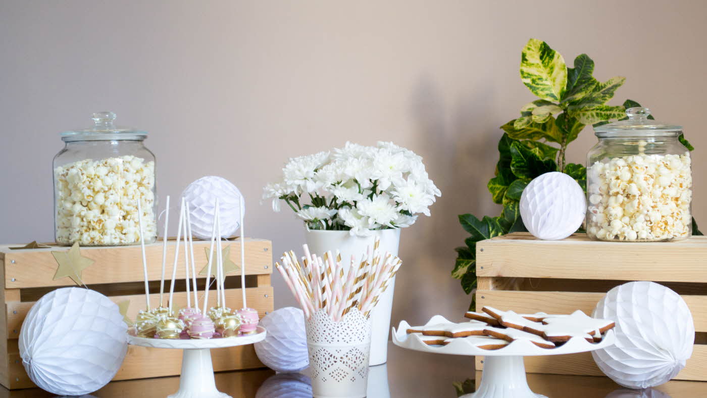 Bord med popcorn, hvite blomster og pom poms.