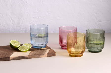 Fire fargede glass står ved siden av et skjærebrett med to limehalvdeler.