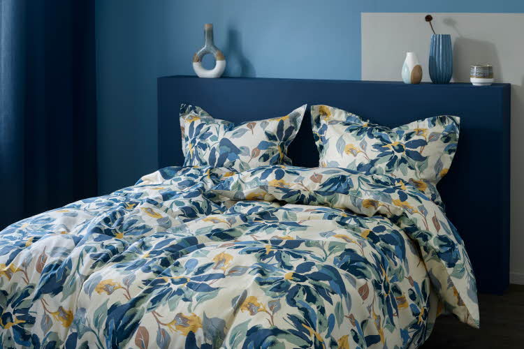 Blomstret, fargerikt sengetøy i blåfarget rom