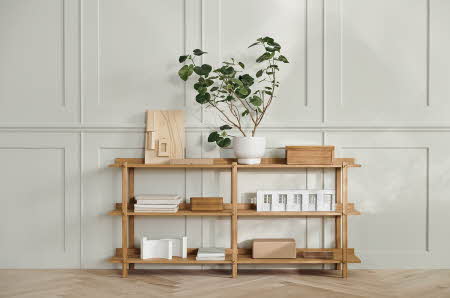 En hylle av tre med en plante på toppen og diverse gjenstander i hyllene