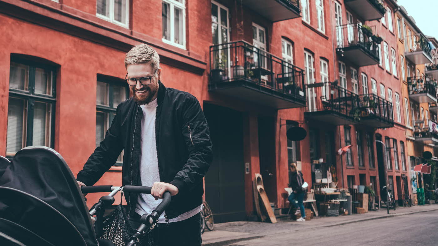 Halvnært bilde av en far som går tur med barnet sitt i vogn