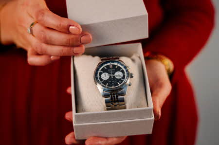 Nærbilde av to hender som holder en boks med en klokke inne i.