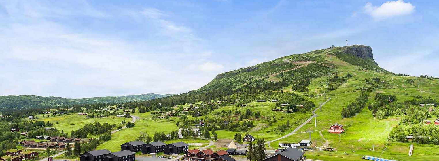 Oversiktsbilde over Høyfjellstunet på Skeikampen man ser bygninger i forgrunnen og det flotte fjellet Skeikampen i bakgrunnen.