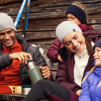 Friluftsfamilie med tre barn og to voksne smiler i uteklær