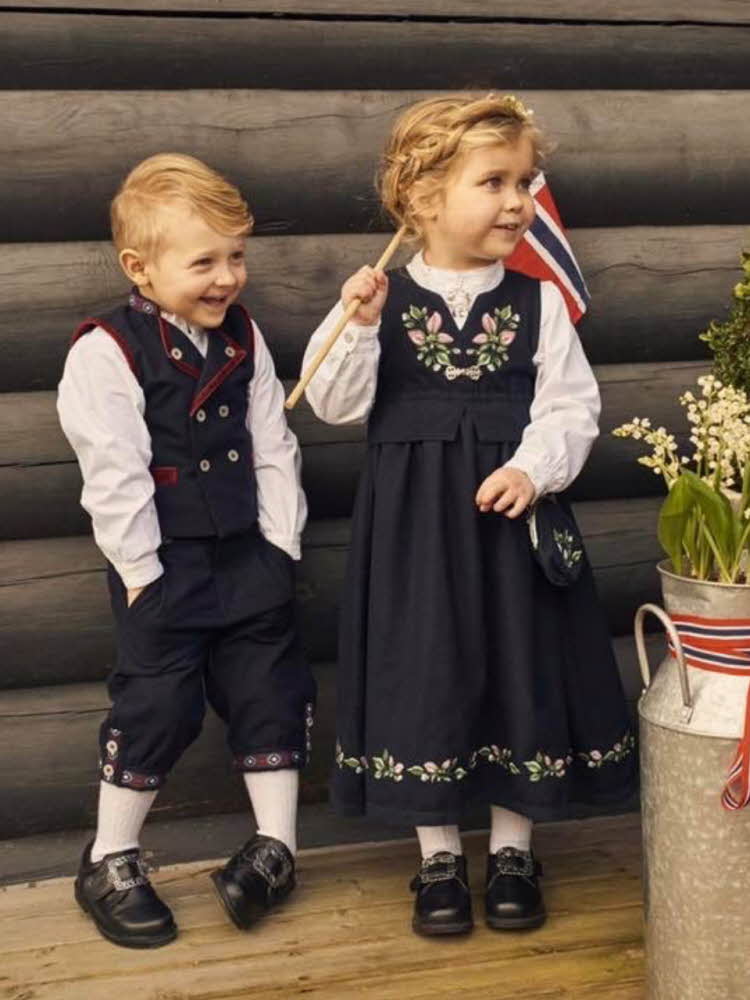 Gutt og jente med festdrakt, jenten holder et norsk flagg