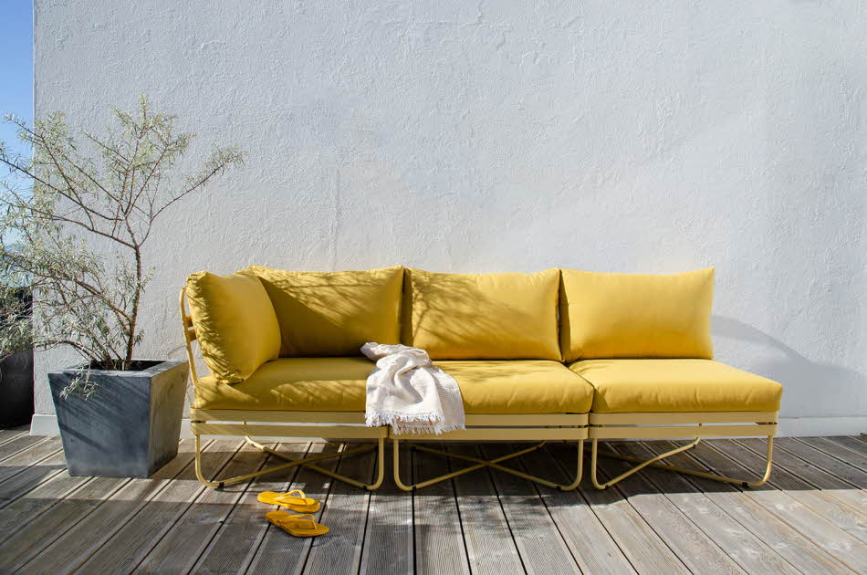 Gull sofa på platt med en grønn plante ved siden av