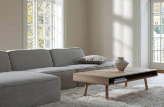 En stue med en stor grå sofa og et stuebord
