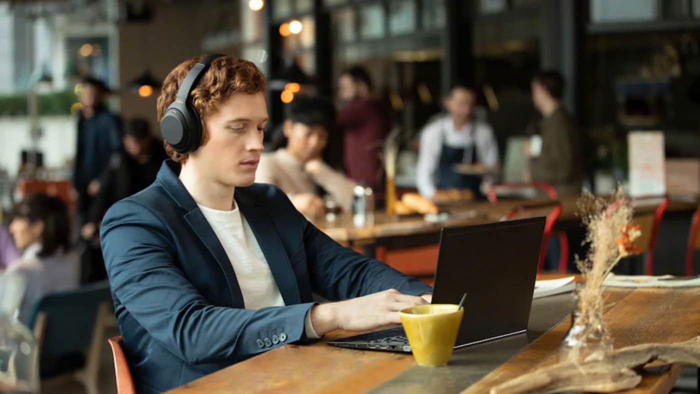 mann som sitter på kafé med headset og laptop