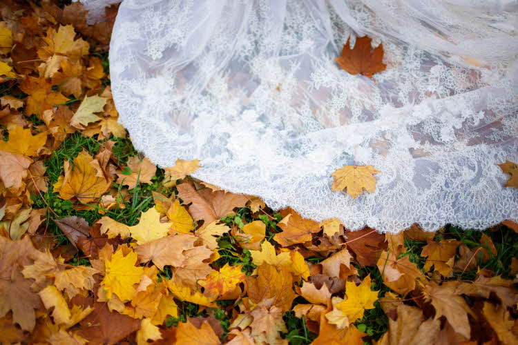 Nærbilde av brudekjolekant i gult høstløv. Foto til artikkel om bryllupsmenyer tilpasset sesong.