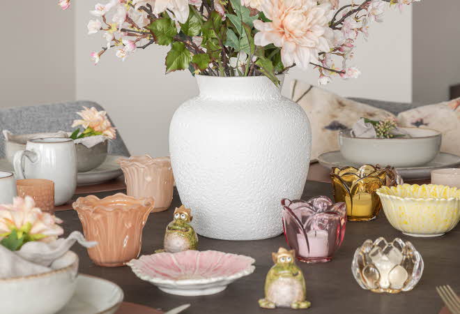 Et bord med mange telyseholdere og en vase med blomster
