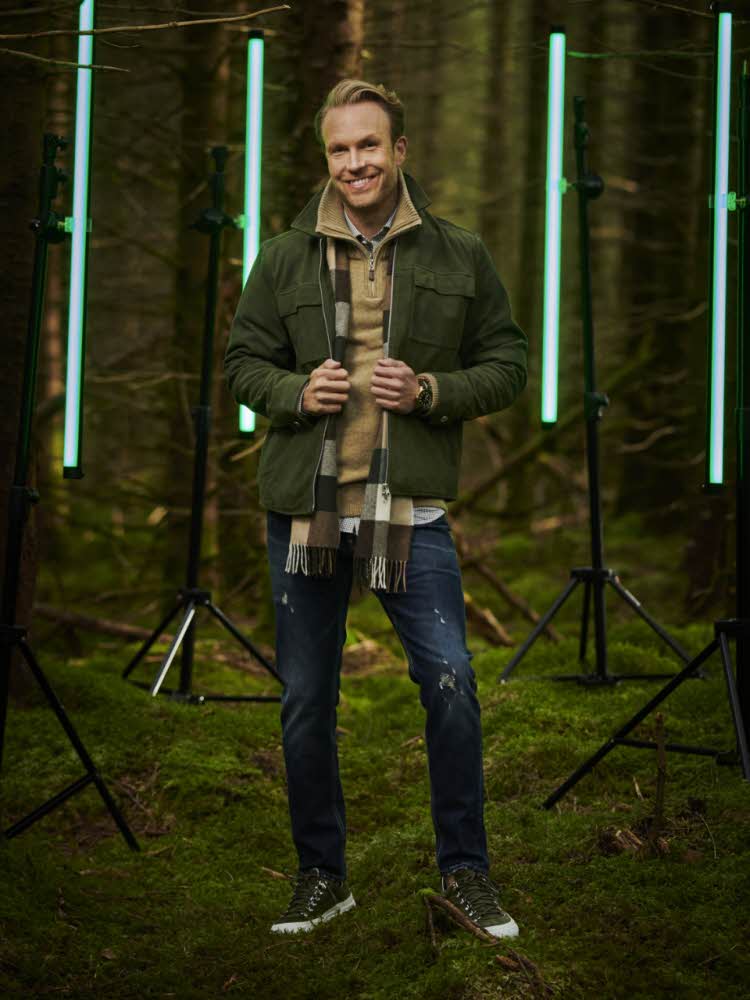Mann står foran grønne lys i skogen
